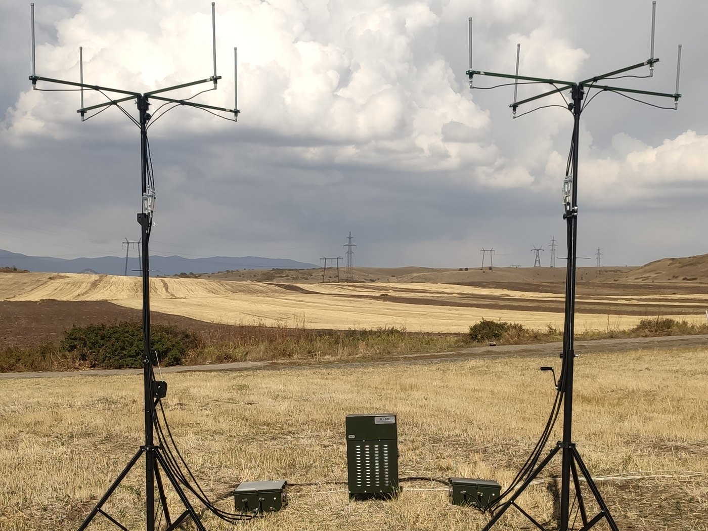 Two directional antenna masts on tripods in open terrain